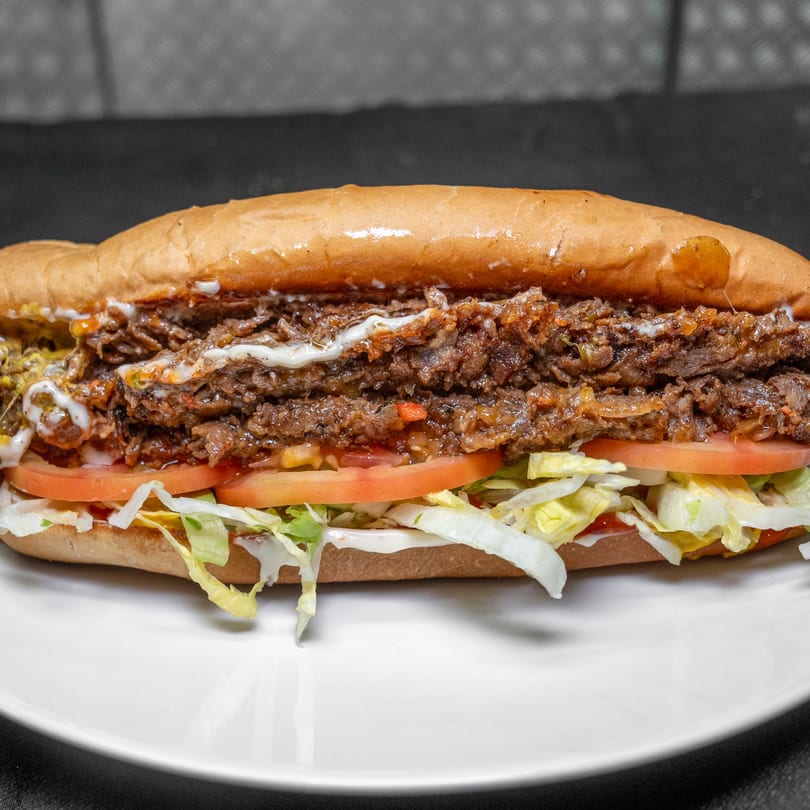 Hearty sub sandwich filled with savory shredded beef, fresh lettuce, tomatoes, and creamy sauce.