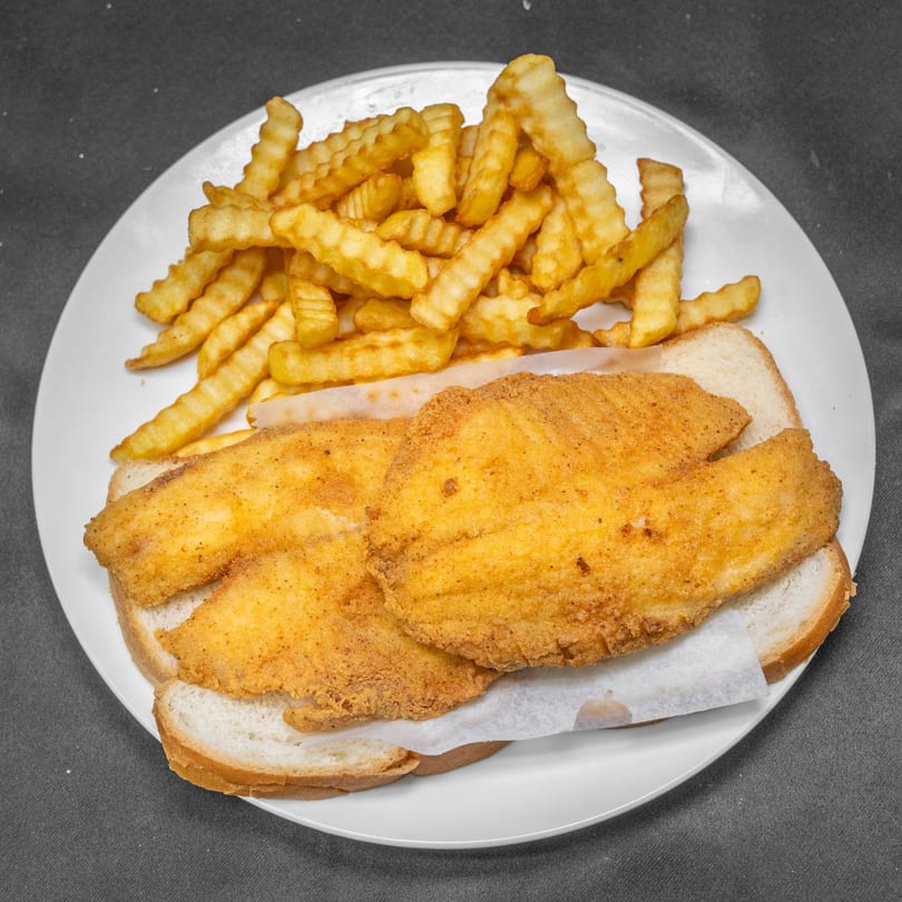 Two fried fish fillets on white bread with crinkle-cut fries on a white plate.