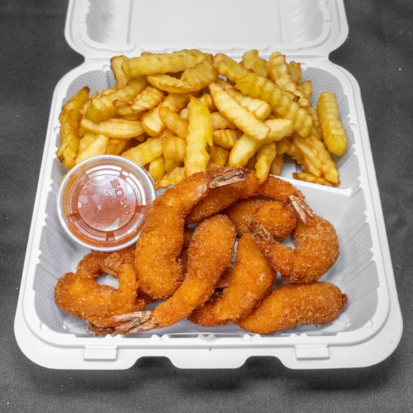 Golden brown breaded shrimp and crinkle-cut fries with dipping sauce in a white takeout container.